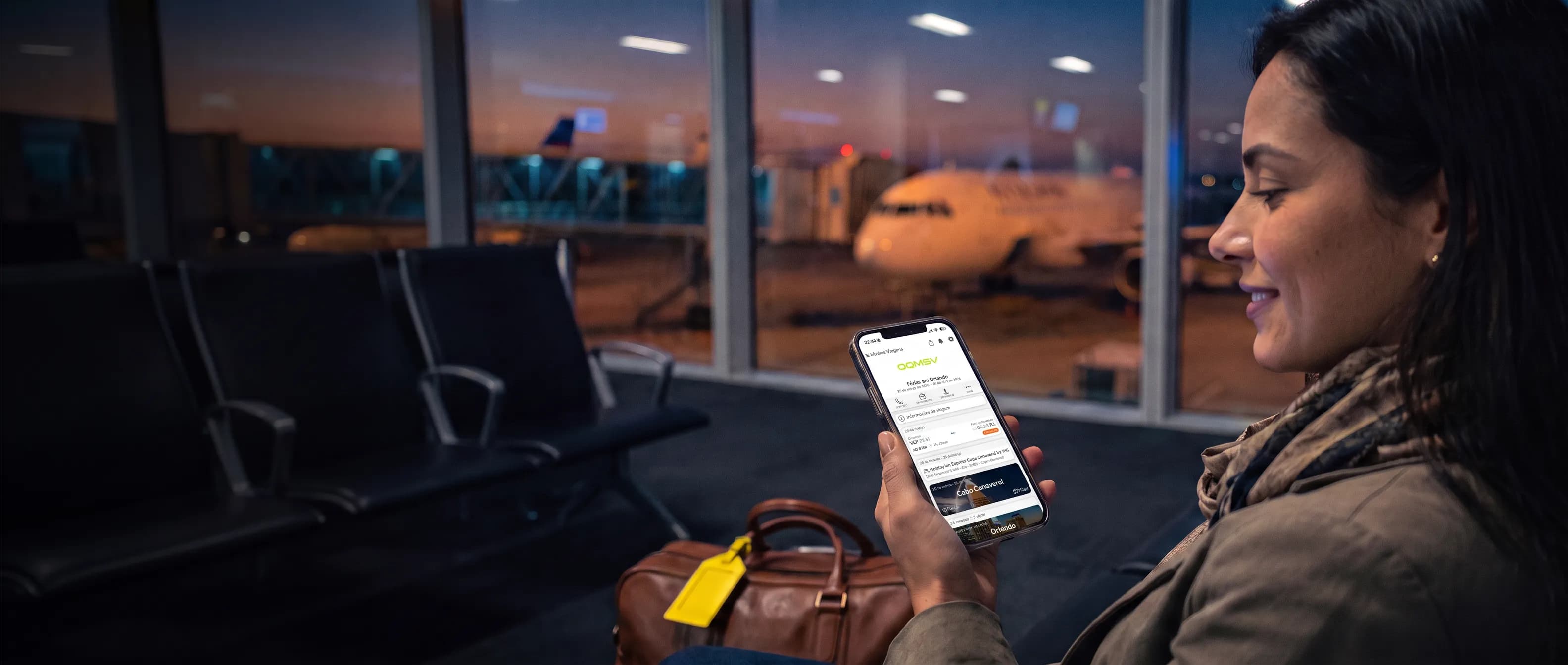Viajante no portão de embarque consultando a viagem no celular, no app com a marca da agência